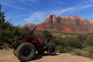 ATV parked on a scenic desert trail with Zion National Park's iconic red rock cliffs in the background, showcasing an off-road adventure in Southern Utah